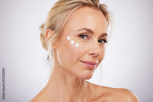Photos Portrait, skincare and face cream for mature woman in studio for wellness, hydration and care on grey background
