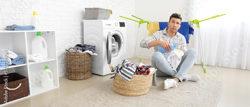 Stressed man doing laundry ...