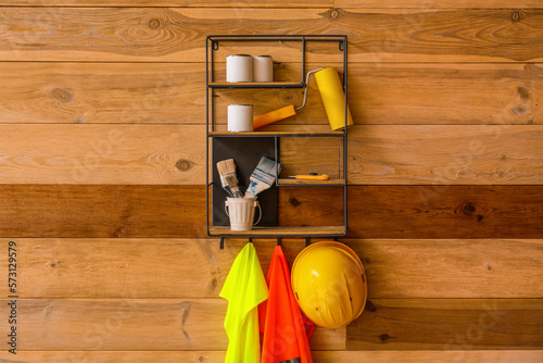 Shelf with builder's supplies and reflective vests on wooden wall