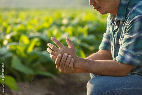 Injuries or Illnesses that can happen to farmers while working. Man is using his hand to cover and press on hand because of hurt,  pain or feeling ill. © SKT Studio