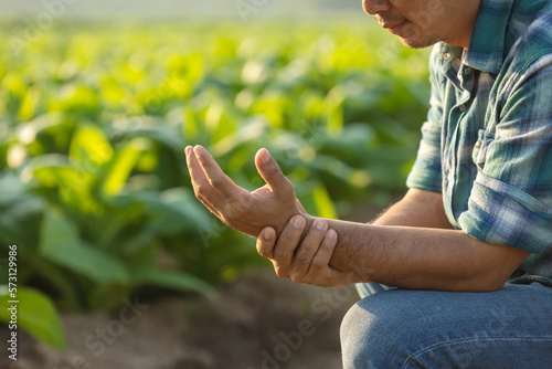 Injuries or Illnesses that can happen to farmers while working. Man is using his hand to cover over wrist because of hurt,  pain or feeling ill. © SKT Studio
