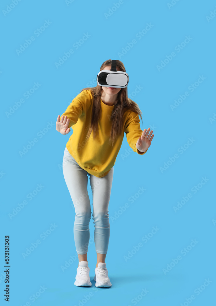 Pretty young woman in VR glasses on blue background Pretty young woman in VR glasses on blue background