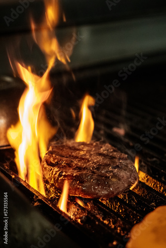 Beef patty covered in fire on a grill