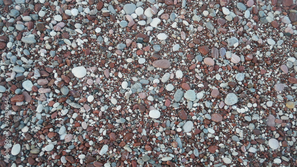 The texture of the sand on the beach. Small stones on the shore. Stone pebble. Beach background The texture of the sand on the beach. Small stones on the shore. Stone pebble. Beach background