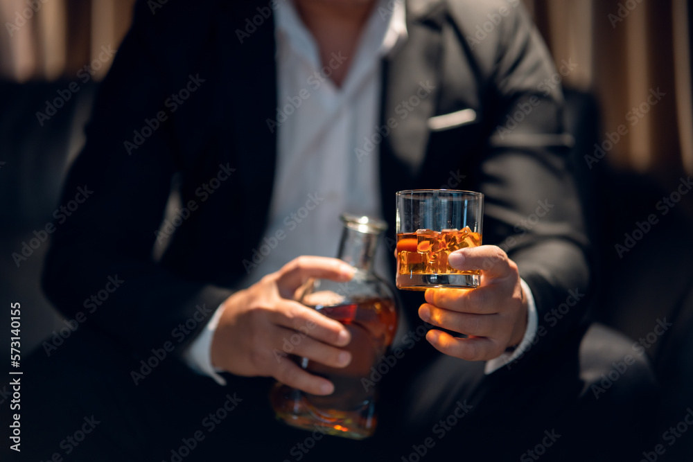 Businessman sitting and holding glass of whiskey