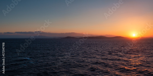 Rocky Island on Mediterranean Sea. Rinia near Mikonos, Greece, Europe. Nature Background Panorama. Sunrise Sky