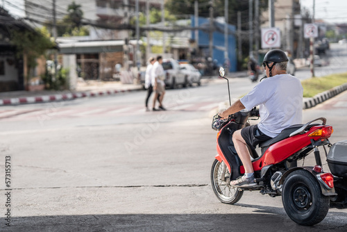 A man from behind on red motorbike in front of the city of Pattaya