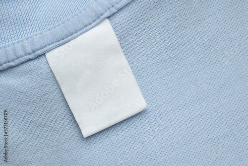 White blank laundry care clothes label on blue shirt fabric background