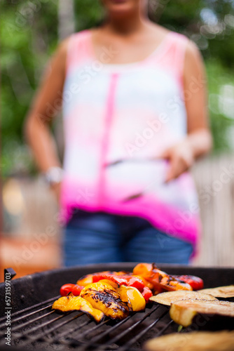 A Japanese American women grills colorful vegetables on a charcoal grill in the backyard. photo