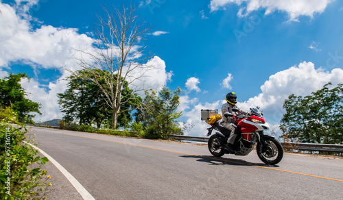 Clouds over biker riding alone on countryside highway on sunny day, Chiang Rai, Mueang Chiang Rai District, Thailand photo