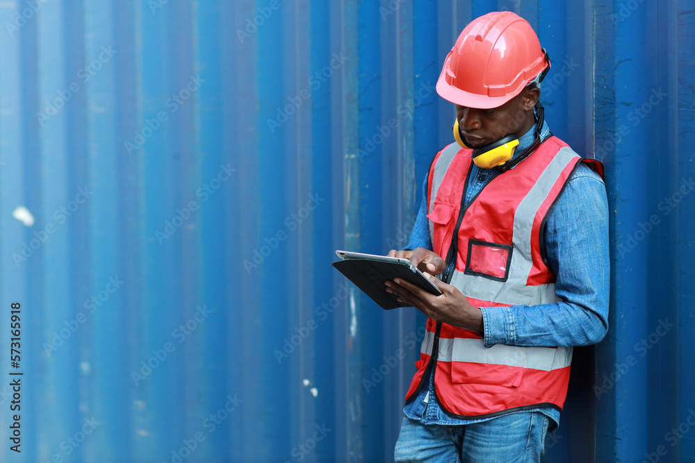 Foreman using tablet and walkie talkie radio control loading containers box. Engineer or worker with safety hat work at container cargo site and checking industrial container cargo freight ship. Foreman using tablet and walkie talkie radio control loading containers box. Engineer or worker with safety hat work at container cargo site and checking industrial container cargo freight ship.
