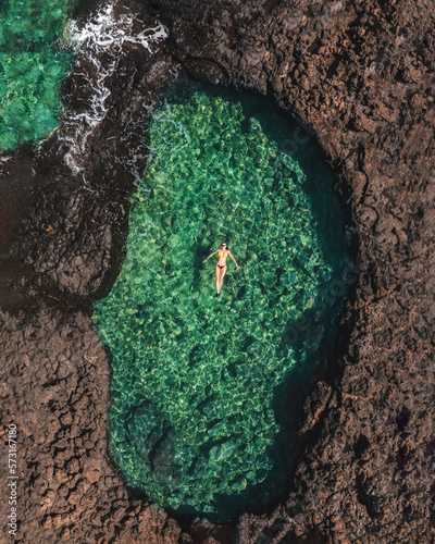 Woman swimming in a clear sea lagoon in Fuerteventura drone shot