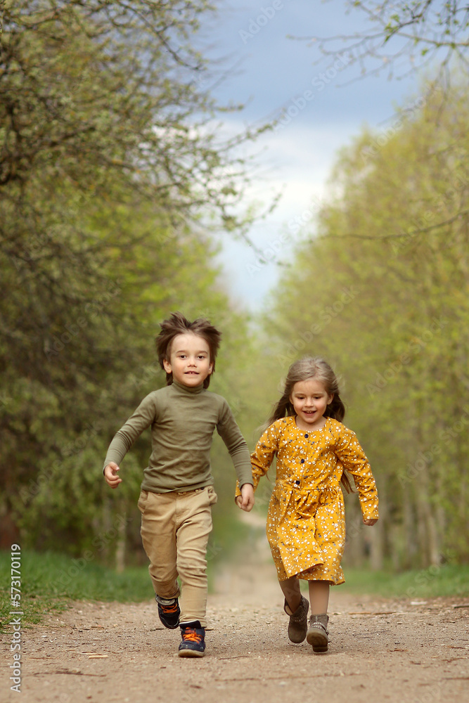 children run through the park holding hands. boy and girl running