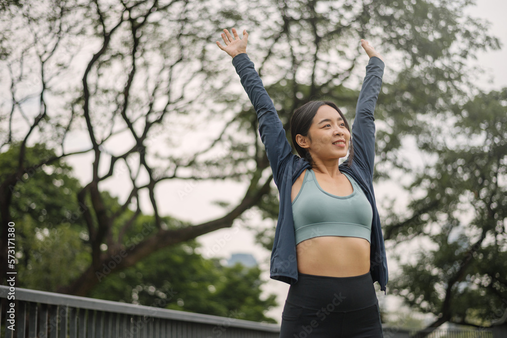 Asian happy woman exercise in park on morning. Healthy female wearing sportswear and stretching body before running in outdoors. wellness lifestyle, outside activities.