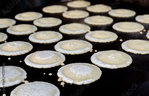 Small pancakes are baked on a hot plate. Street market