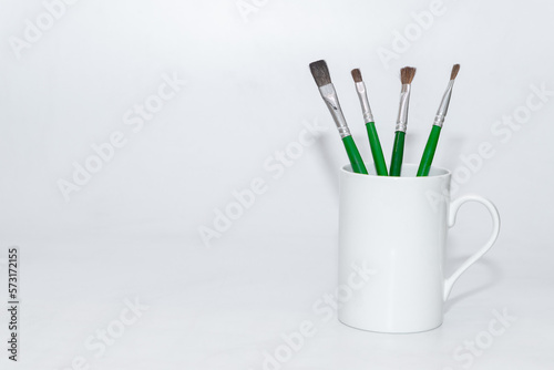 Paint brushes kept standing in a cup with white background and copy space