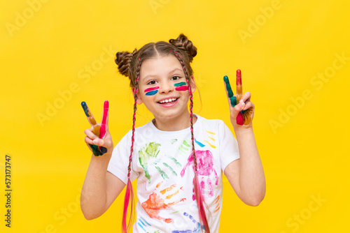 The child got dirty in multi-colored paint. A little girl with pigtails loves to paint. Paint drawing lessons. Children's creativity.