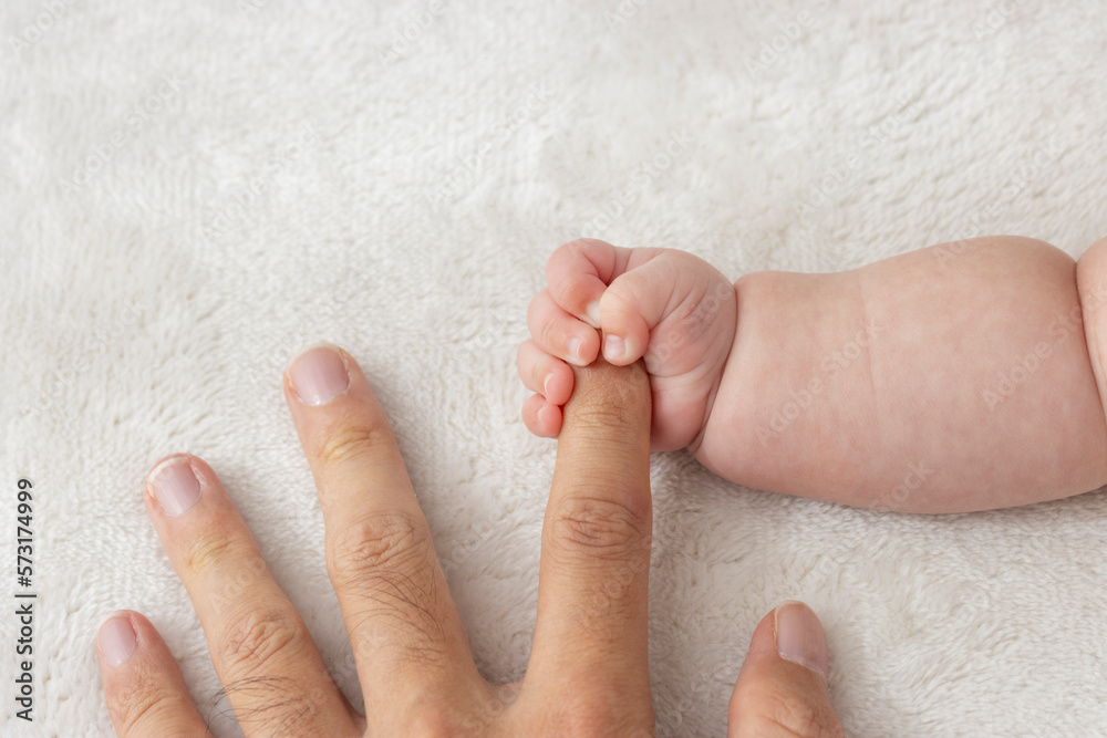 父親の指を握りしめる赤ちゃんの右手(0歳2か月、男の子、日本人)
