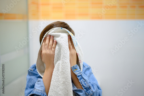 Unrecognizable child up close drying his face with a towel