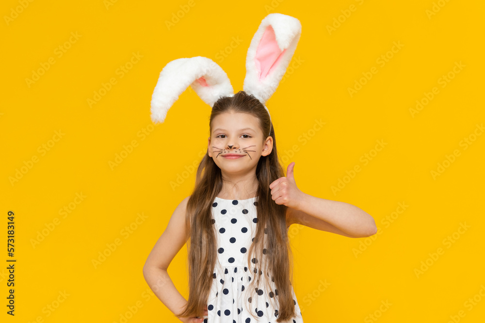 Cute attractive girl with Easter bunny ears gave a thumbs up, Easter day and egg coloring.
