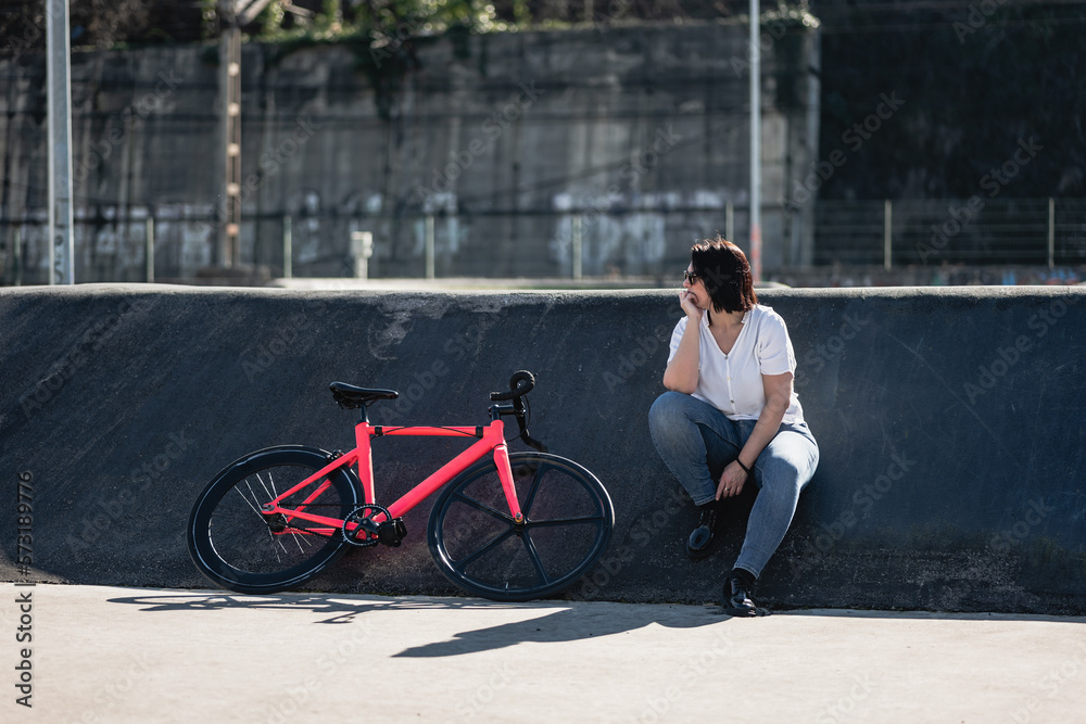 Obraz premium woman resting next to a bicycle in the skate park
