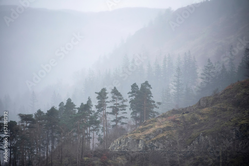 Beautiful calm peaceful Winter landscape over Thirlmere in Lake District with mist and layers visible in the distance photo