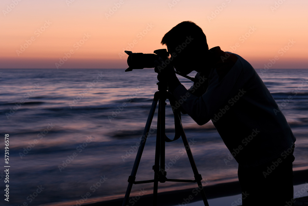 Silhouette of a photographer at dawn by the sea
