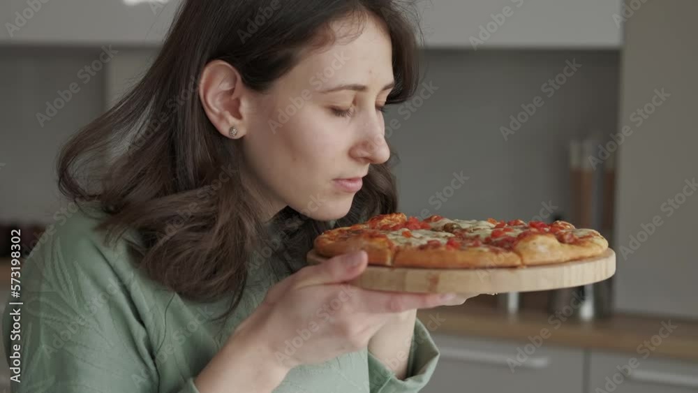 Close up video of young woman smelling fresh baked pizza with mozzarella. Close up video of young woman smelling fresh baked pizza with mozzarella.