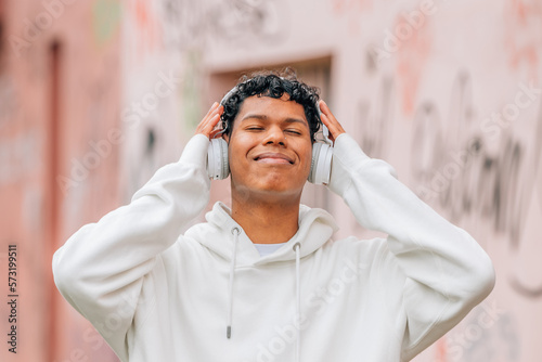 young latin man with headphones enjoying happy outdoors photo