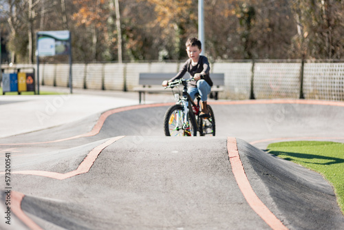 A young child rides the new Park BMX pump track on his bike on a summer evening