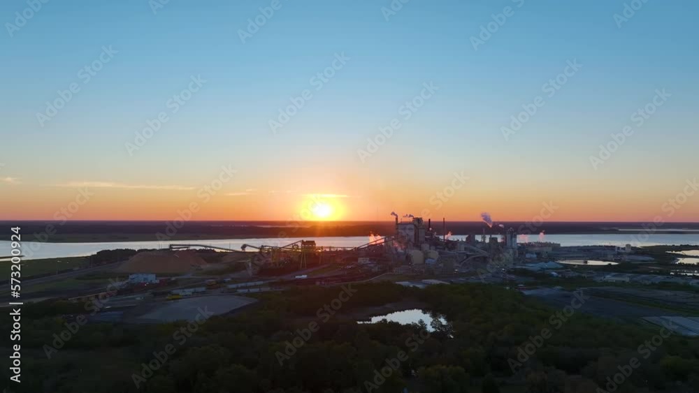 Aerial view of wood processing factory with smoke from production process polluting atmosphere at plant manufacturing yard. Industrial site at sunset Aerial view of wood processing factory with smoke from production process polluting atmosphere at plant manufacturing yard. Industrial site at sunset