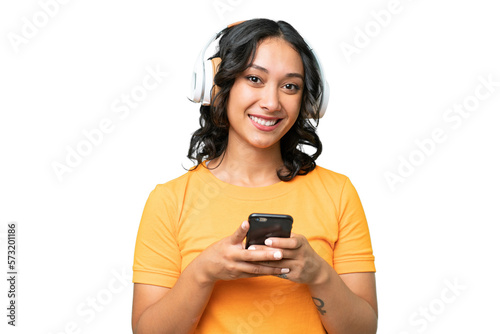 Young caucasian Argentinian woman over isolated background listening music with a mobile and looking front