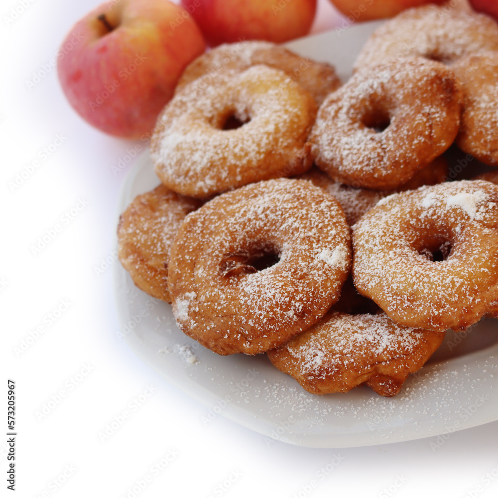 Homemade deep fried apple rings with batter sprinkled with powdered sugar on a plate isolated on white with fresh apples Homemade deep fried apple rings with batter sprinkled with powdered sugar on a plate isolated on white with fresh apples
