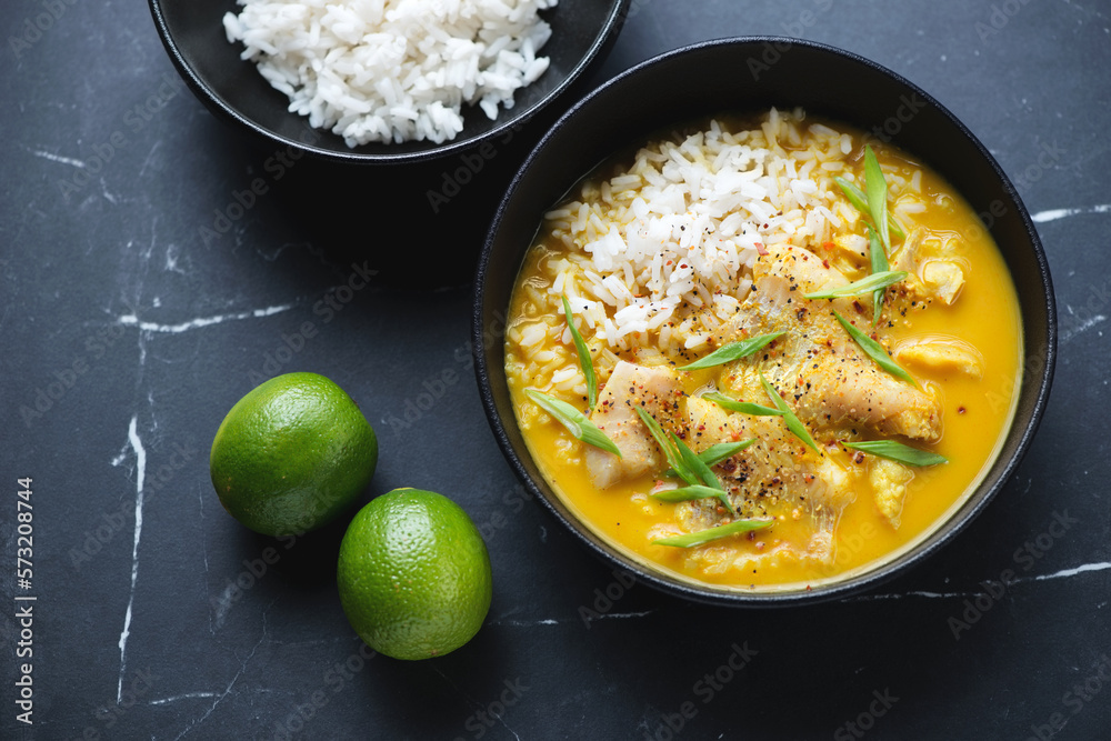 Bowls with fish yellow curry and white rice on a black marble background, high angle view, horizontal shot Bowls with fish yellow curry and white rice on a black marble background, high angle view, horizontal shot