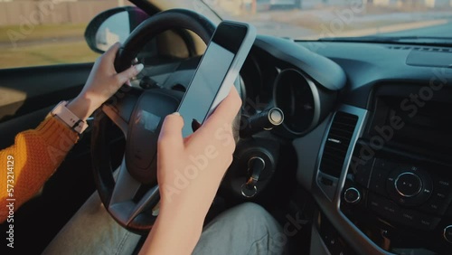 Hands of unrecognizable woman driver using mobile phone while driving car, distracted driving, don't text and drive
