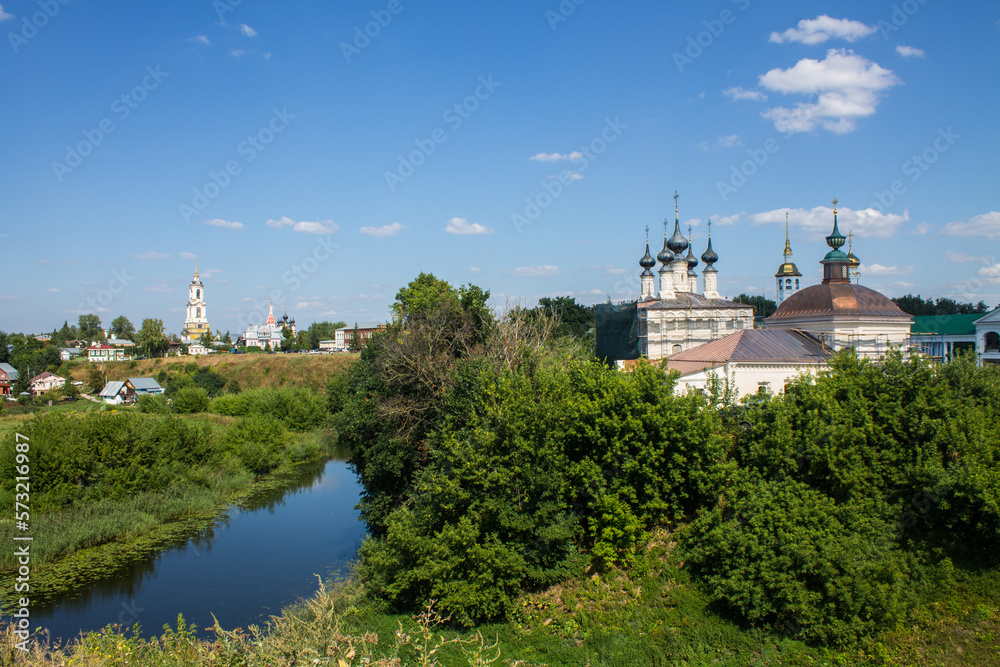 Panoramic view of the historical architecture of Suzdal in the Vladimir region among the green foliage of trees and Kamenka river on a sunny summer day and a space for copy
