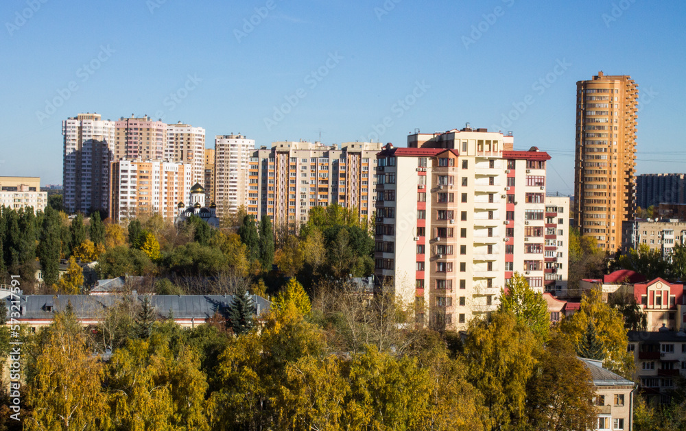 Fototapeta premium Urban beautiful landscape - panoramic view of residential multi-storey modern houses among autumn trees on a sunny October day in Reutov Moscow region and copy space