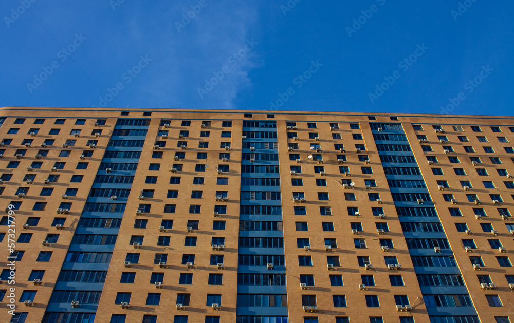 Fototapeta premium A wall with windows of a modern multi-storey house in a close-up in Reutov near Moscow and a space for copying on a sunny day