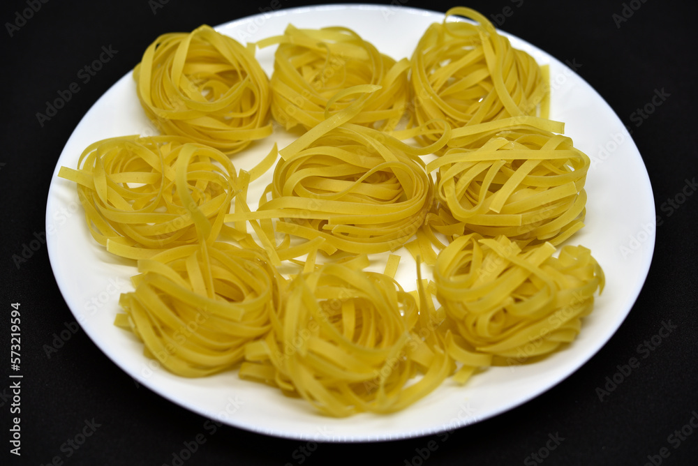 Dry pasta on a white plate. Wheat pasta. Dry pasta on a white plate. Wheat pasta.