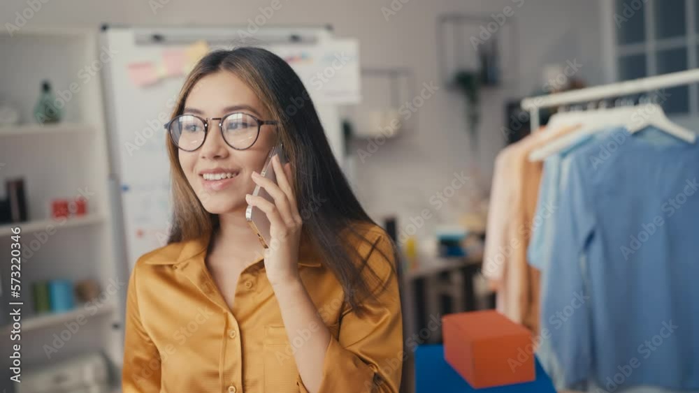 Young asian woman clothing designer solving business issues using phone Young asian woman clothing designer solving business issues using phone