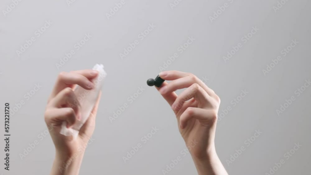 Hands holding earphone and wiping, cleaning with wiper, cloth, disinfesting earbud, closeup. Hands holding earphone and wiping, cleaning with wiper, cloth, disinfesting earbud, closeup.