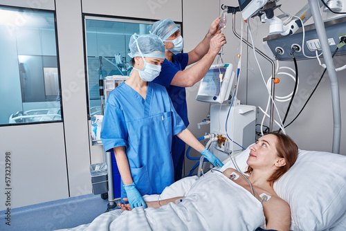 Intensive care patient. Nurses attending to female patient in intensive care unit of hospital photo