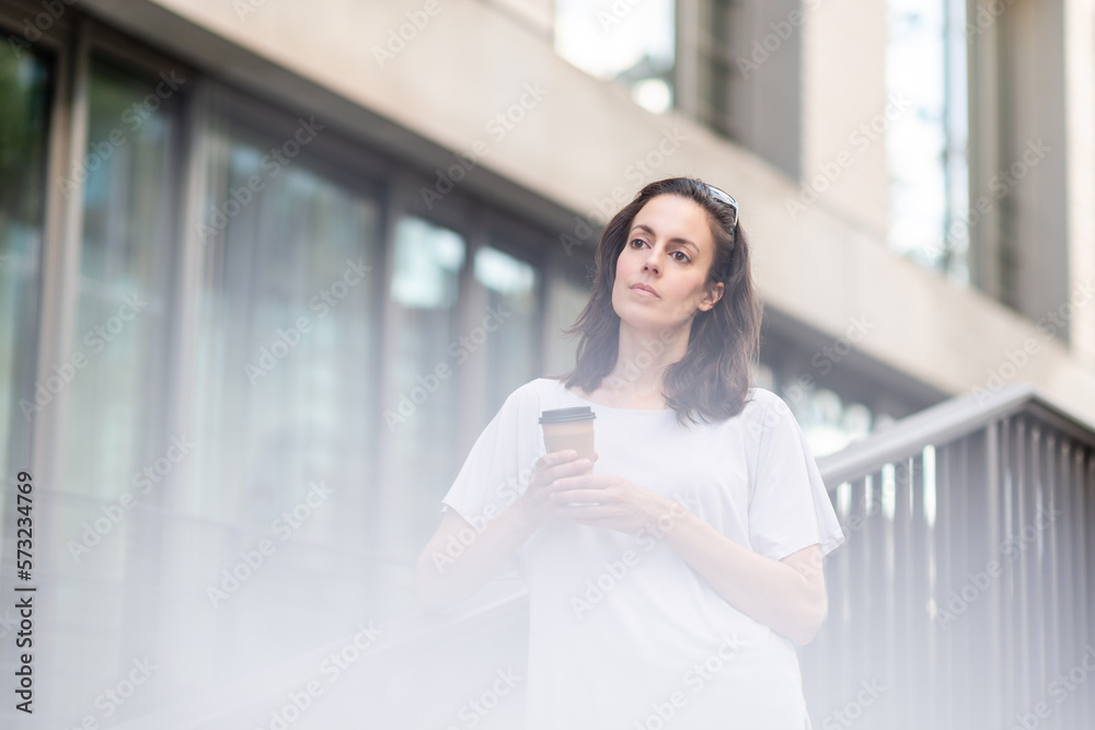 Thoughtful young female holding coffee mug while standing on balcony Thoughtful young female holding coffee mug while standing on balcony
