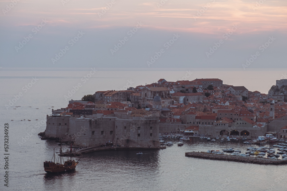 Iconic aerial view of Dubrovnik old town at dusk, pirate ship, vintage edit, Croatia