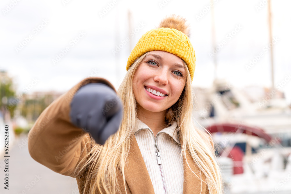 Young pretty blonde woman wearing winter jacket at outdoors points finger at you with a confident expression