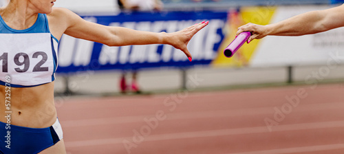 women relay team passing of baton in track and field
