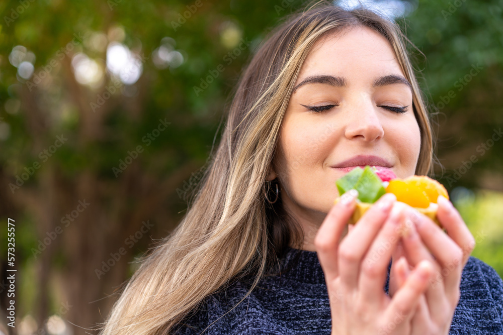 Young pretty Romanian woman holding a tartlet at outdoors Young pretty Romanian woman holding a tartlet at outdoors