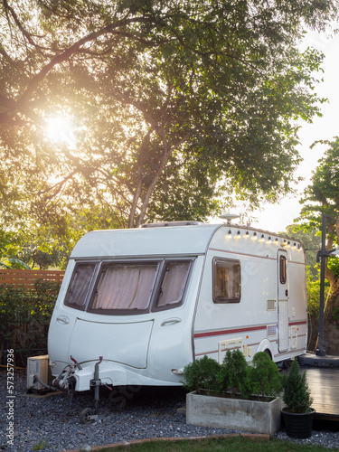 Caravan car park in the garden decoration with festive wire light bulbs with nobody, vertical style. Relaxation nature camping and sleep in the motorhome trailer. Family vacation travel concept.