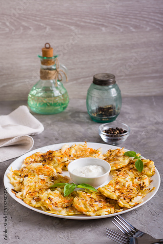 Vegetable fritters from cabbage and carrots and sauce on a plate. Vegetarian food. Vertical view