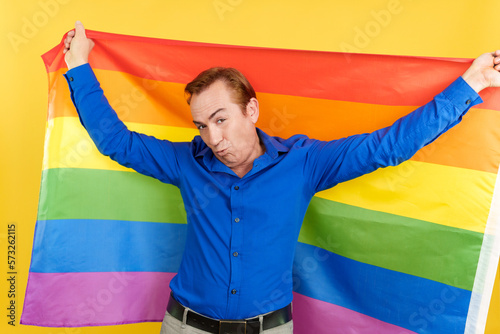 Mature man blowing a kiss raising a lgbt rainbow flag